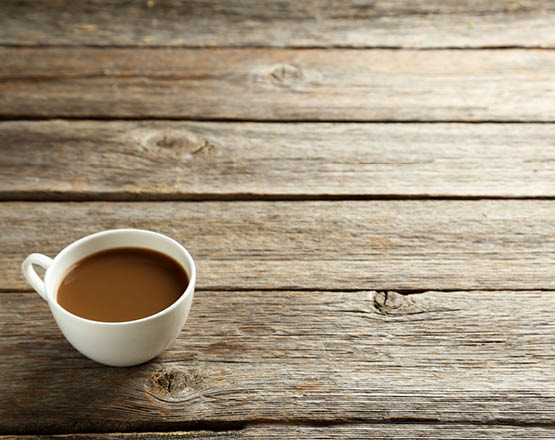 Kaffee in einer Tasse auf einem Massivholztisch